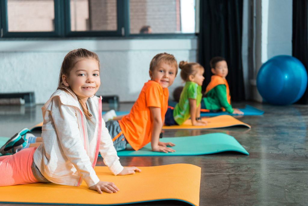 Image: A group of kids working out on exercise mats at the gym, showcasing the importance of fitness in developing leaders.